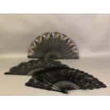 Three large c 1890’s fans, all on black wood, the first with a deep border of painted butterflies,