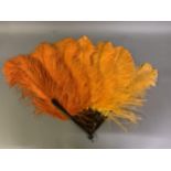 A 1920’s shaded orange ostrich feather fan, light to dark left to right, the monture faux