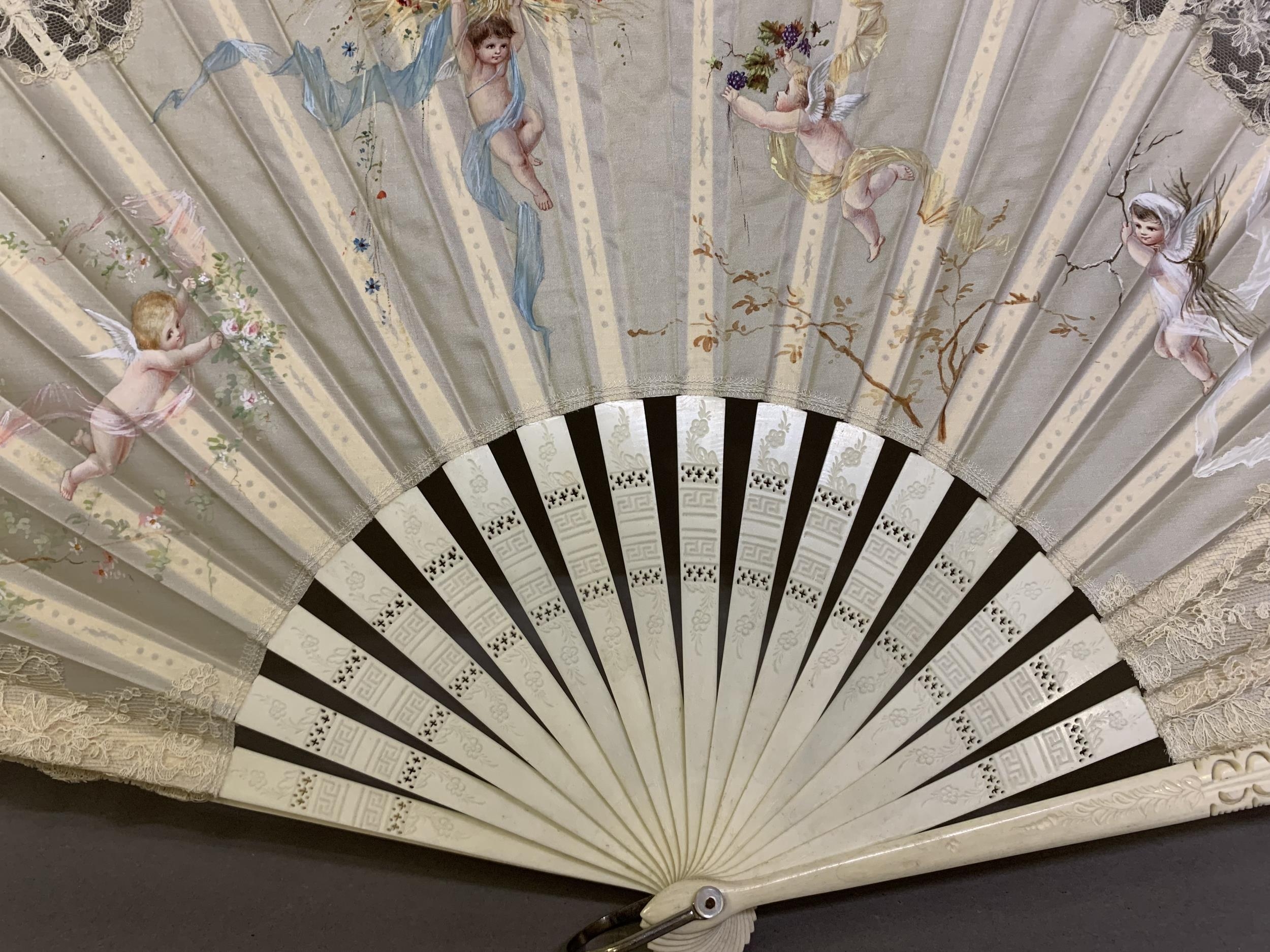 c1890s, a large incised bone fan, the cream silk leaf painted with winged cherubs carrying fruits - Image 4 of 4