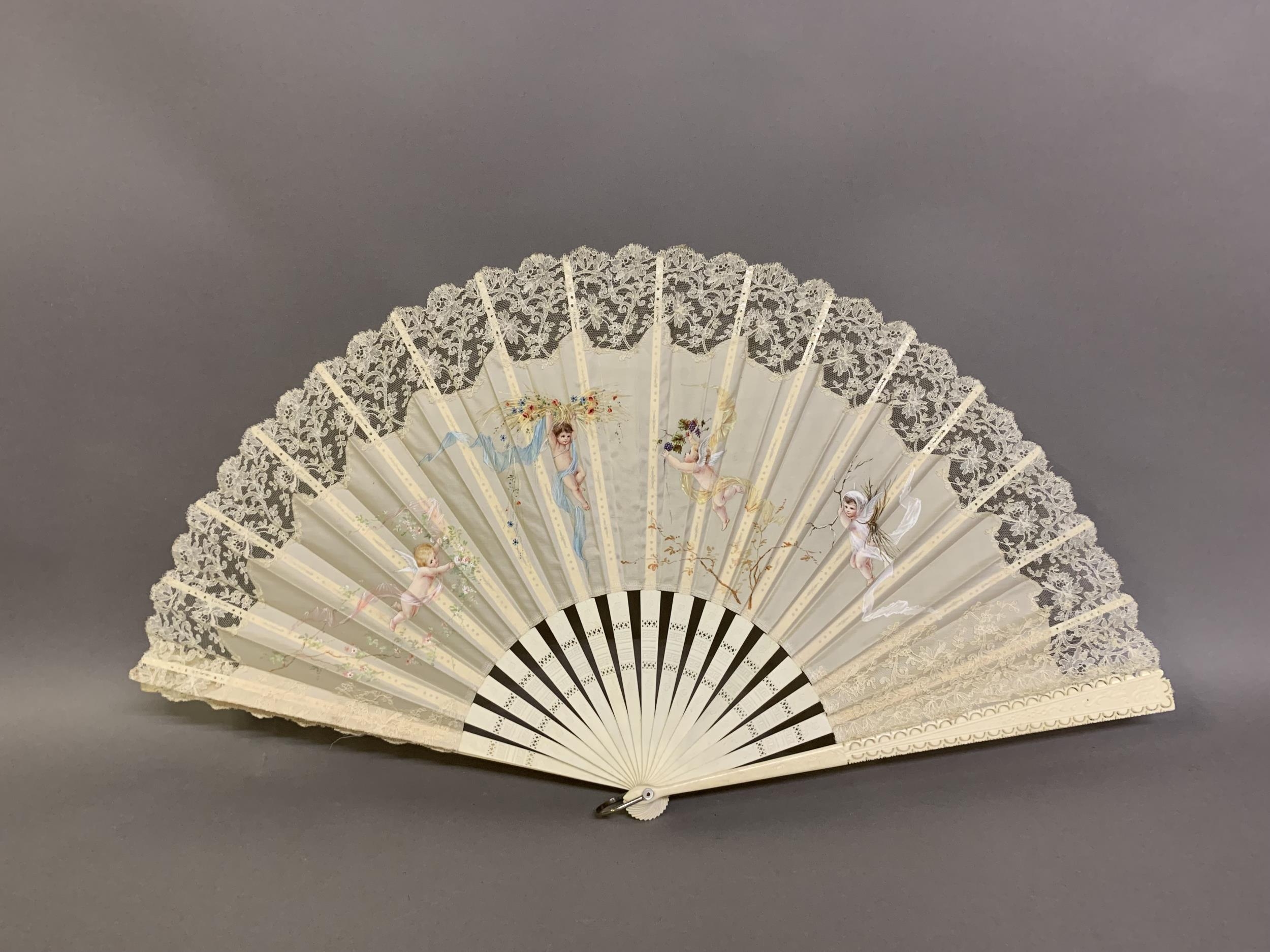 c1890s, a large incised bone fan, the cream silk leaf painted with winged cherubs carrying fruits