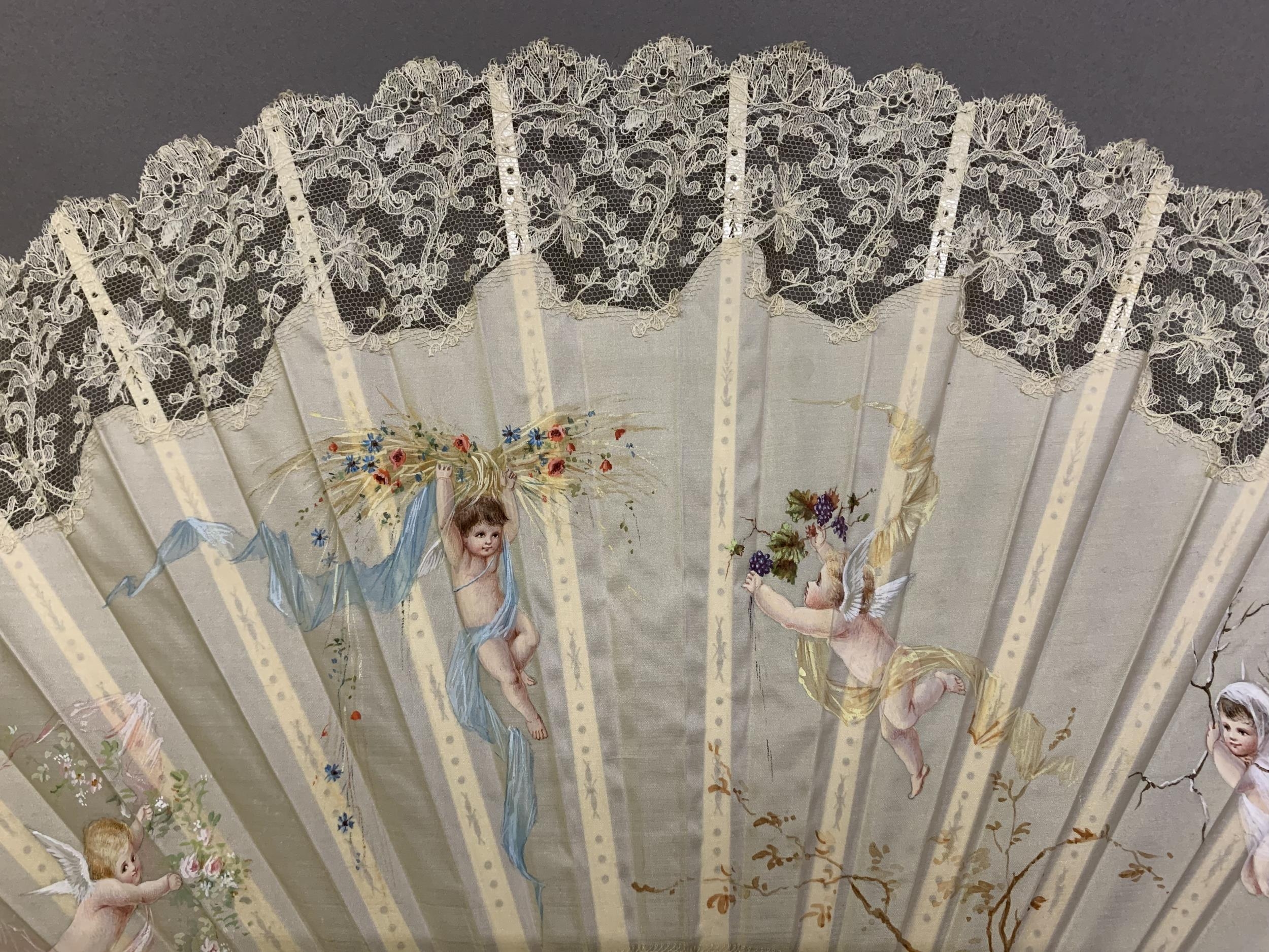 c1890s, a large incised bone fan, the cream silk leaf painted with winged cherubs carrying fruits - Image 2 of 4