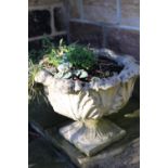 A pair of cast garden urns foliate moulded on stiff leaf socles and square bases, 50cm by 42cm high