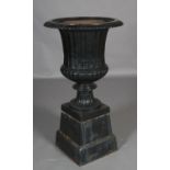 A large cast iron garden urn, having an egg and dart rim, fluted and lobed body on a knopped and