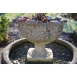 A pair of cast urns with petallated rims, ringed and stiff leaf socle on square base 37cm wide x