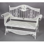 A wrought iron garden bench having an arched back, scroll over arms, with open woven panels, 137cm