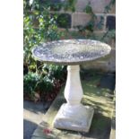 A cast garden table, the circular top having an impressed foliate surface, on pedestal base and on