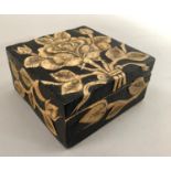 Carved hardstone box and cover inlaid with rose on black ground with entwining foliage