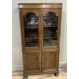 A 1920's oak bookcase having tow arched glass panelled doors above two indented panel door