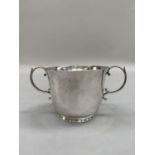 A George V silver sugar bowl of plain form with splayed rim, two c-scroll handles and circular foot,