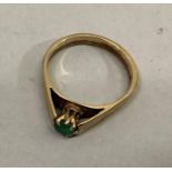 A single stone emerald ring in 9ct gold, the circular faceted stone claw set flanked by broad