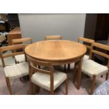 A 1970's teak extending dining table of circular outline with six dining chairs