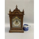 A late Victorian oak cased mantel clock having an arched pediment with three finials above a