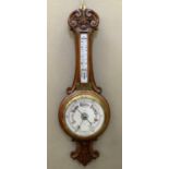 An Edwardian oak cased barometer thermometer carved with foliage