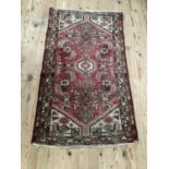 A Persian rug of rose pink ground filled with geometric motifs and flower heads within a zig zag