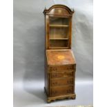 Reproduction yew wood finished bureau display cabinet having an arched profile with urn finials,