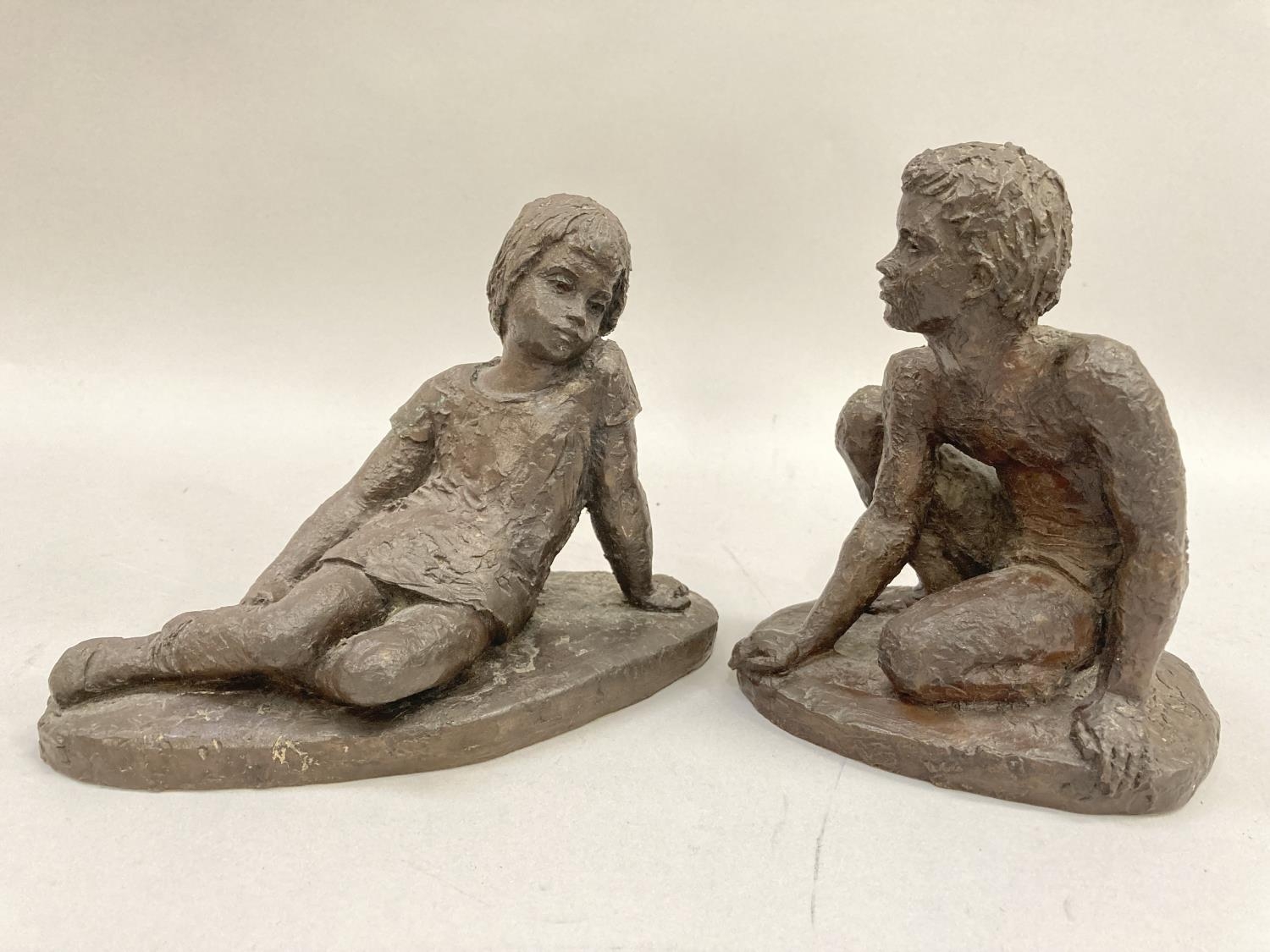 Two bronze effect resin figures of a young girl reclining and a young boy crouched on one knee, 15cm