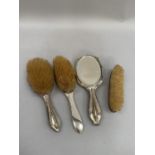 Four silver backed dressing table items, including two hair brushes, one mirror