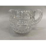A cut glass water jug modelled as a golf ball and etched with the 19th Hole in a circular cartouche,