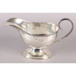 A LATE VICTORIAN SILVER SAUCE BOAT of oval outline, C scroll handle, reeded edge and stepped foot,