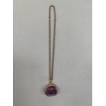 A George V 9ct rose gold watch fob mounted with a three sided spinning facetted purple paste, hung