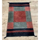 A modern wool rug of square and rectangular panels in mid green, fox red and black, measuring