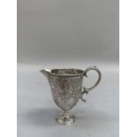 A Victorian silver cream jug, foliate scroll chased with double c-scroll handle and stepped circular