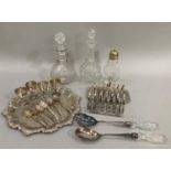 Two glass decanters and a sugar caster, two silver plated toast racks, egg cups, tray, salad servers