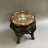 A Chinese hardwood urn stand, the octagonal surface inlaid in mother of pearl above a carved foliate