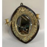 An ebonised wall mirror with brass surmount cast with birds and foliage over bevelled glass