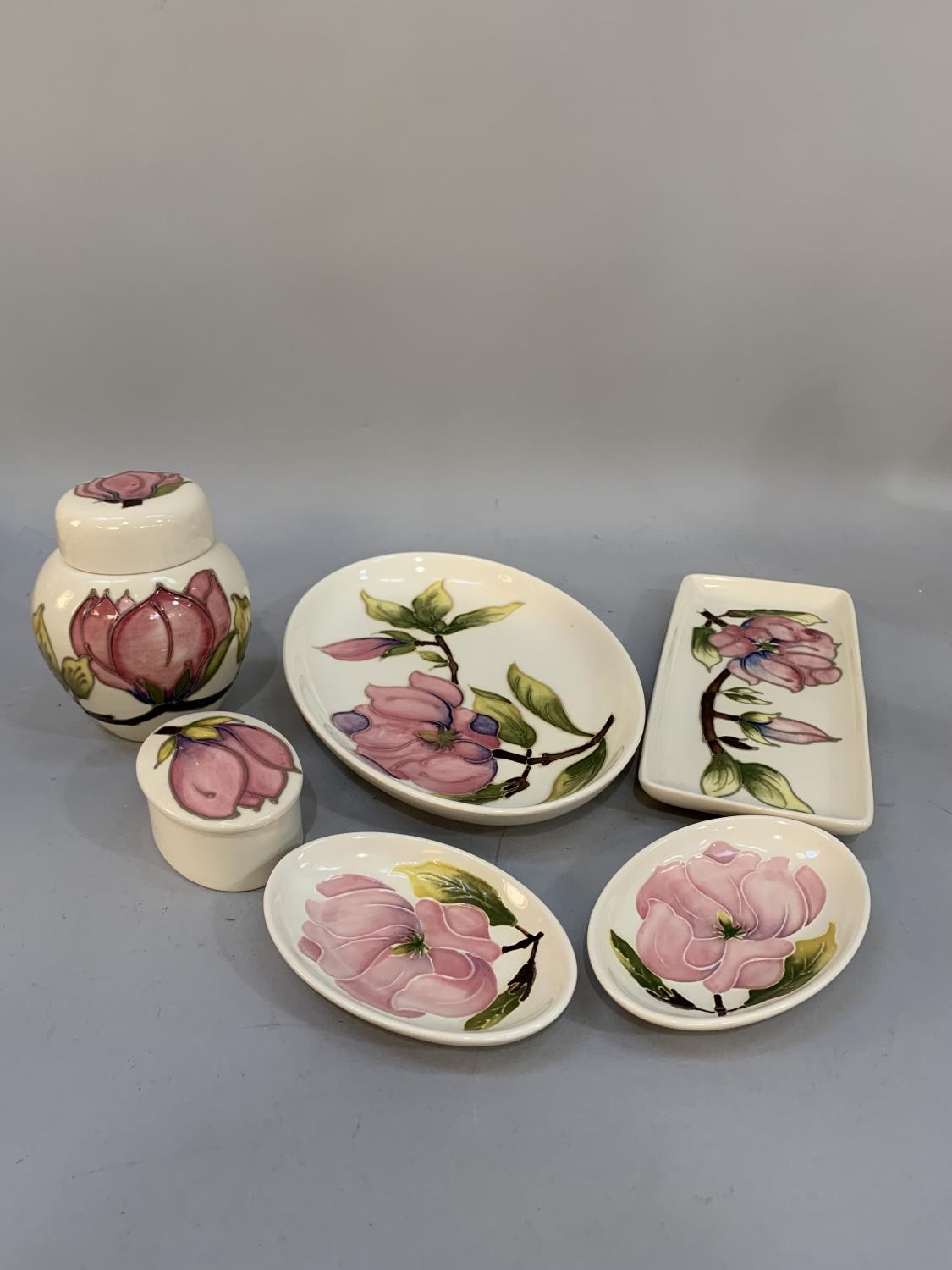 Six items of Moorcroft magnolia tube lined and glazed in pink on a cream ground comprising lidded