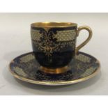 A Coalport china cabinet cup and saucer, the dark blue ground enriched in gilt and decorated