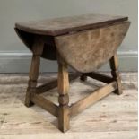 An oak drop leaf occasional table with adzed surface on square framing with applied triangle
