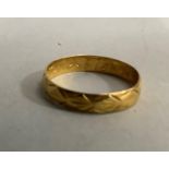 A wedding ring in 22ct gold with engraved pattern, approximate width 3.5mm, approximate weight 1g