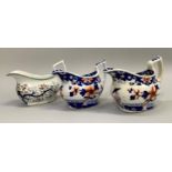A trio of Newhall cream jugs of graduated size variously decorated in reds and blues with flowers