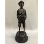 A reproduction bronzed figure of a young boy wearing a cap, hands in his pockets and trousers rolled