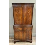 Mahogany drinks cabinet of serpentine outline having a two door cupboard above a pull slide and