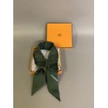 Hermès: a silk necktie in olive green and grey, with attached oval gold metal ring, the design of