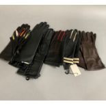 Seven pairs of soft dark leather gloves, some unused, some with colours