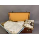 A vintage brown leather suitcase containing a quantity of Christening gowns and other clothing,