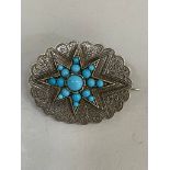 A Victorian silver star brooch set with graduated blue paste cabochons raised against a foliate