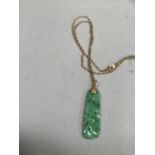 A jade pendant, the oblong pierced and carved stone drilled at the top and hung on a 9ct gold Prince