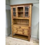 A pine and glazed kitchen cabinet having two cupboards and open shelf to the centre above an