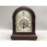 An early 20th century mantel clock of domed outline, the silvered dial with Arabic Roman numerals,