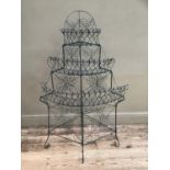 A wire corner garden tiered plant stand with three recesses on four scroll feet, 75cm wide x 129cm