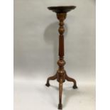A mahogany torchere having a turned and reeded column on tripod base