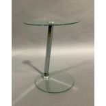 A glass topped occasional table of circular outline on a chrome support and glass circular base,
