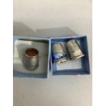 Three early to mid 20th century silver thimbles variously set with enamel and cornelian, total