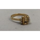 A topaz and diamond ring in 18ct gold, claw set to the centre with a step cut topaz flanked by
