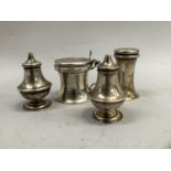 An Edward VII four piece silver condiment set including mustard pot with green glass liner, two salt