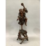Japanese root carving of a dancing figure holding a coin balanced on one foot on naturalistic root